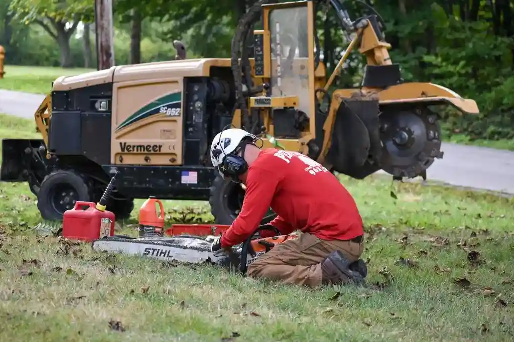 Penn West crew member fueling a chainsaw beside a Vermeer stump grinder in Mercer County, PA